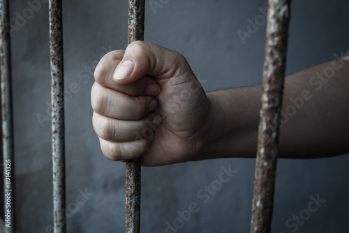 hands of jail holding prison bars