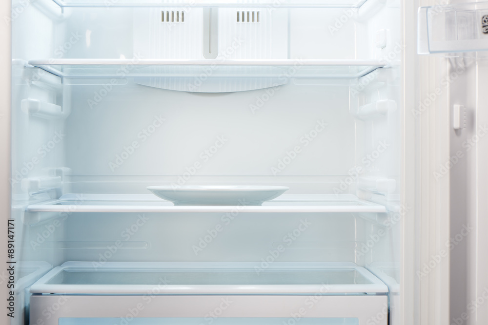 Empty white plate in open empty refrigerator. Weight loss diet concept. Empty white plate in open empty refrigerator. Weight loss diet concept.