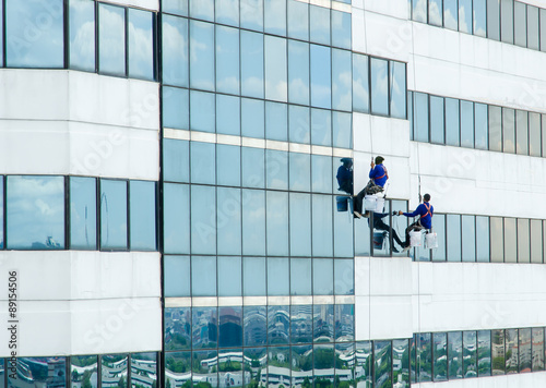 group of workers cleaning windows on building high tower