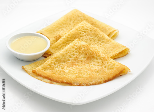 Russian pancakes with sweet milk isolated on white