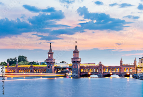 Oberbaum Bridge with subway and boat on the river Spree at night, Berlin