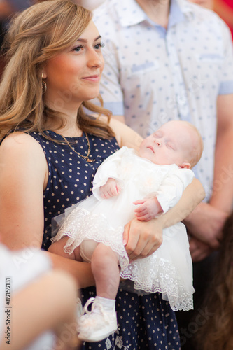 Happy mother with baby on christening ceremony in church