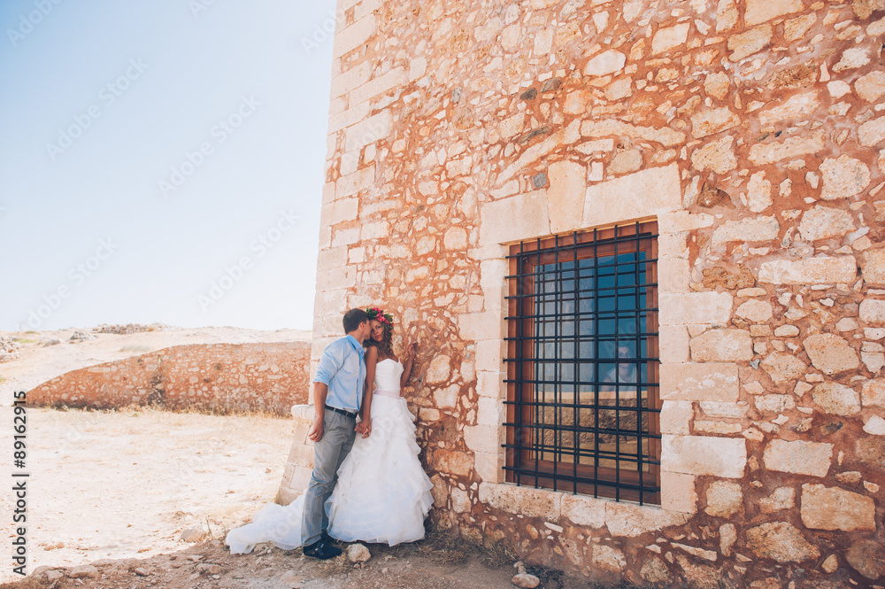 couple in love, bride and groom standing near the stone wall