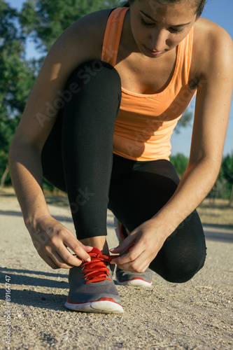 Woman tying laces of running shoes