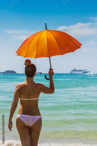girl with orange umbrella on the beach in Thailand