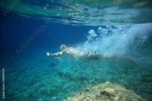 underwater view of man diving in crystal clear coastal waters and landscape
