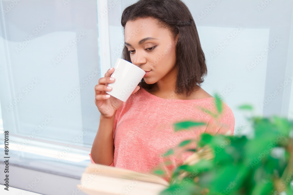 Attractive lady drinking tea and reading book