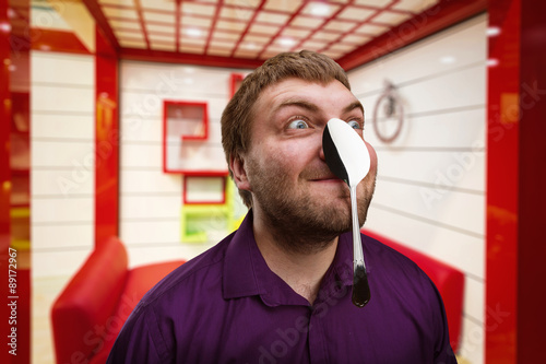Obraz na plátne Adult man holds a spoon on his nose