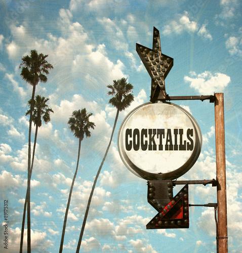 aged and worn vintage photo of cocktails sign and palm trees