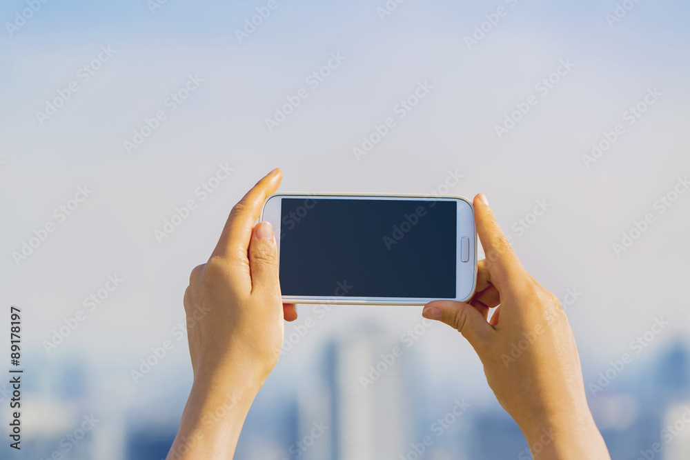 Person holding a smartphone on a city background