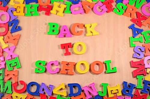 Back to school written by colorful letters on a wooden backgroun