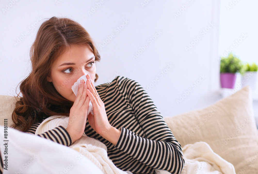 Portrait of a sick woman blowing her nose while sitting on the Portrait of a sick woman blowing her nose while sitting on the
