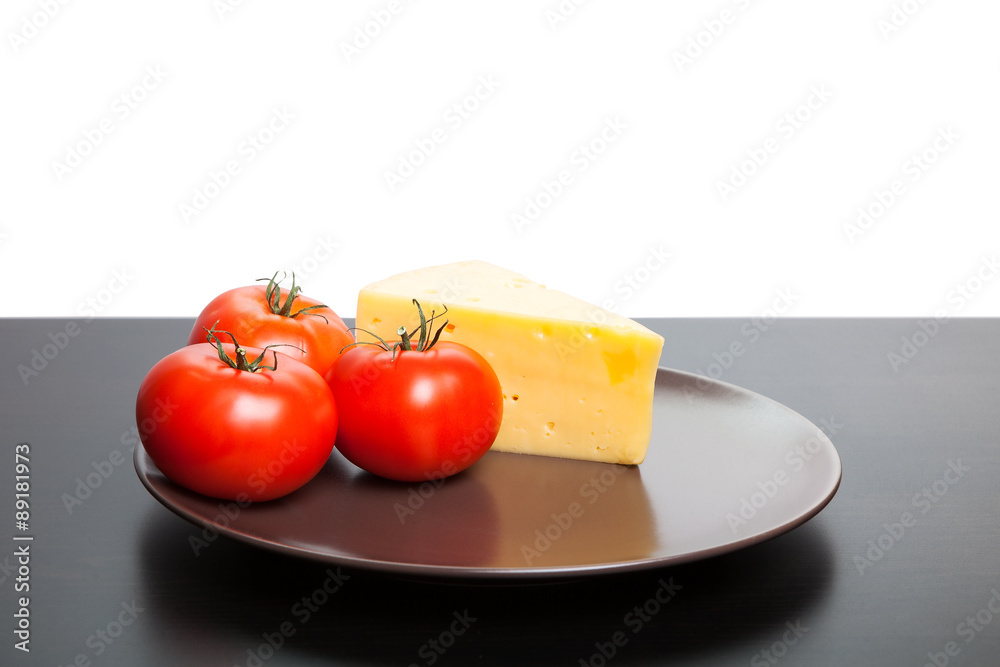 Piece of cheese and tomatoes lying on the plate. Piece of cheese and tomatoes lying on the plate.