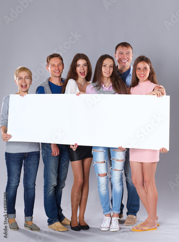 Happy young group of people standing together and holding a