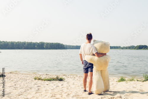 Young handsome man is fooling around with a teddy bear. photo