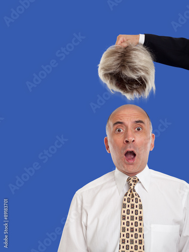 Bald man revealed by removing the toupee photo