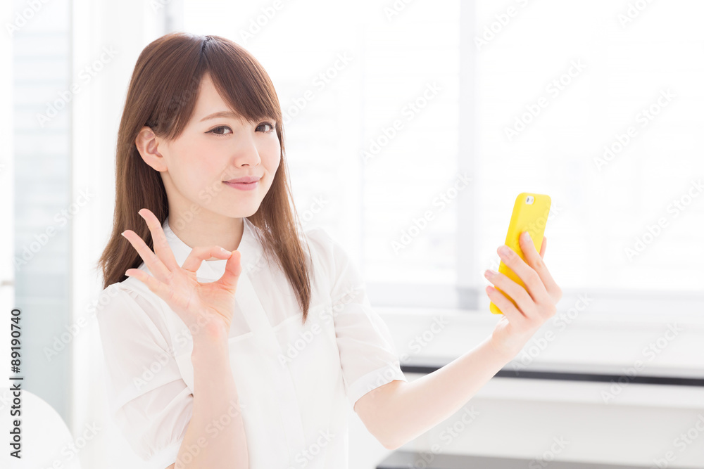 部屋でスマホを見る女性