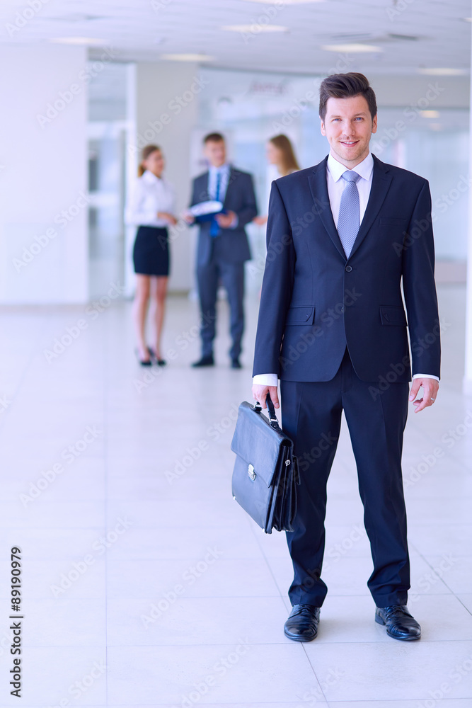 Portrait of young businessman in office with colleagues in the Portrait of young businessman in office with colleagues in the