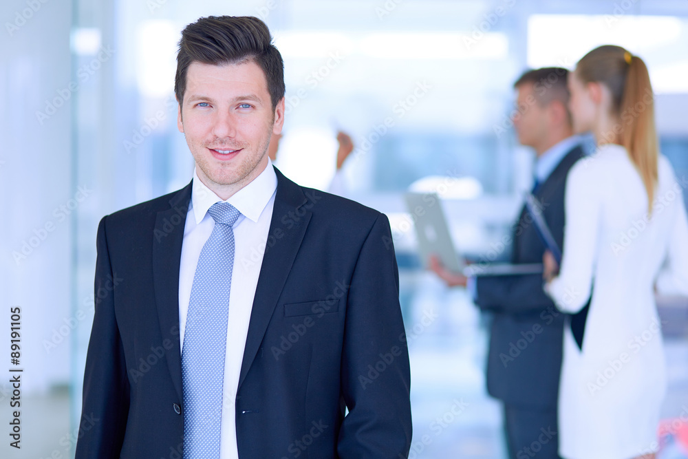 Portrait of young businessman in office with colleagues in the