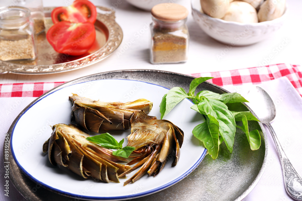 Roasted artichokes on plate, on kitchen table background