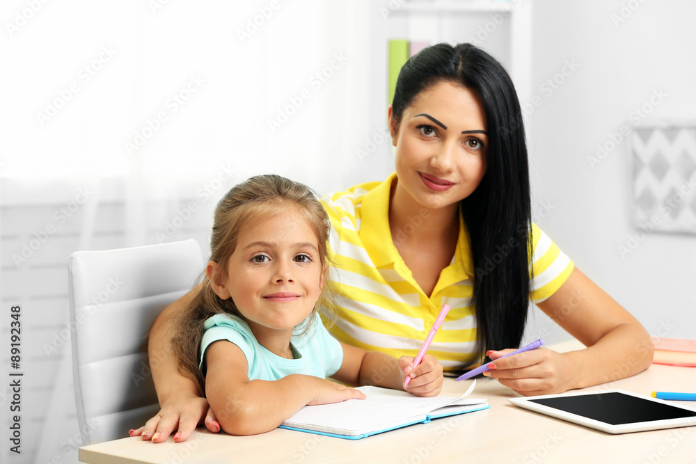 Beautiful school girl doing homework with mother at home Beautiful school girl doing homework with mother at home