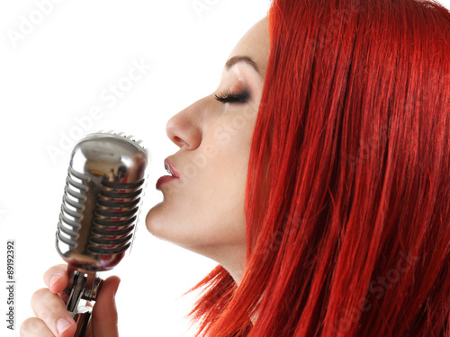 Beautiful young woman singing with microphone isolated on white