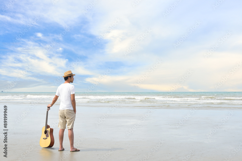 Young man with an acoustic guitar on the beach Young man with an acoustic guitar on the beach