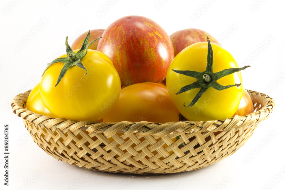 Red and yellow tomatoes in wicker oval shape