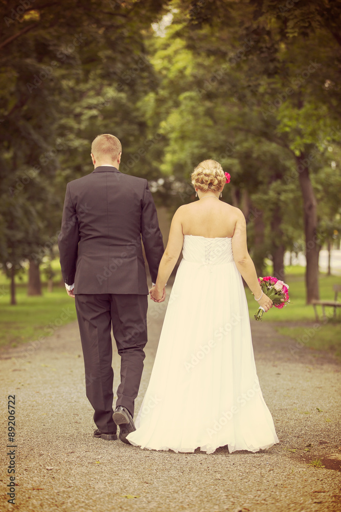 Just married. A newly weds walking towards a future together in the park. Image has vintage effect applied.