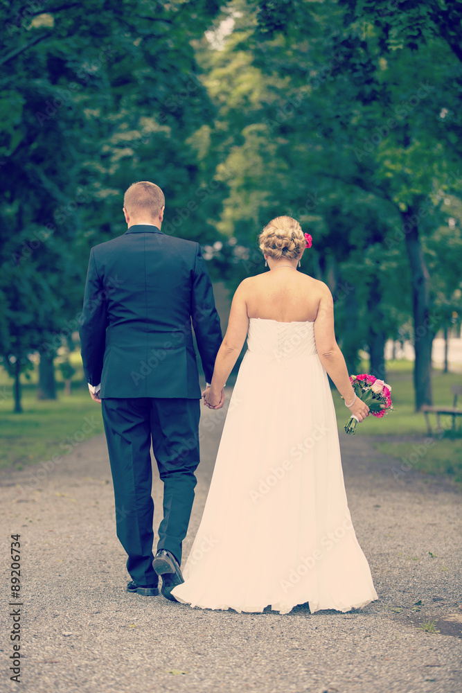 Just married. A newly weds walking towards a future together in the park. Image has vintage effect applied. Just married. A newly weds walking towards a future together in the park. Image has vintage effect applied.
