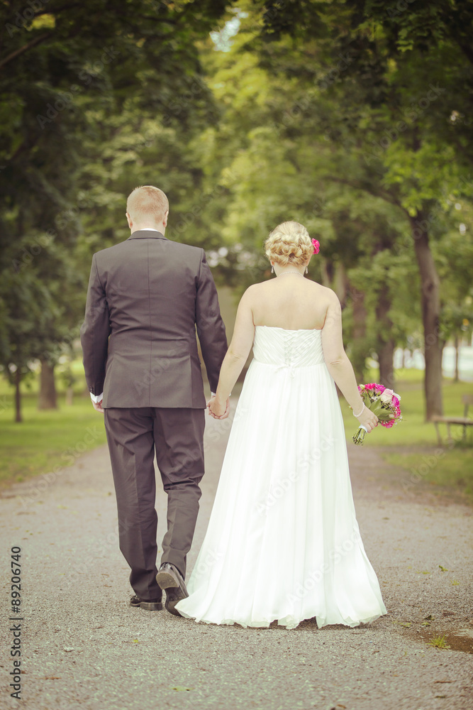 Just married. A newly weds walking towards a future together in the park. Image has vintage effect applied.
