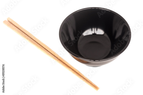 Black ceramic bowl with wooden shopsticks isolated