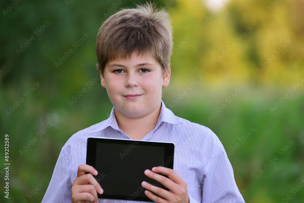 Teen boy with  tablet computer at nature