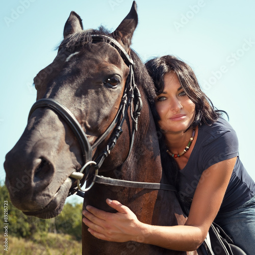Portrait of beautiful young dark-haired woman on a horse.