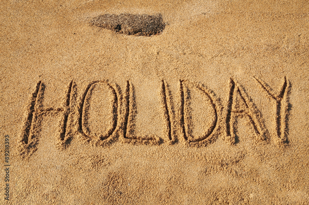 Fototapeta premium The word Holiday written in the sand on the beach