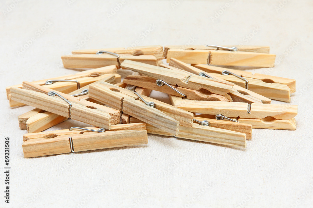 Wooden clothespins heap on white fabric background. Wooden clothespins heap on white fabric background.