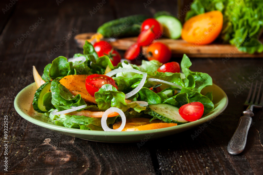 салат из свежих овощей в тарелке на деревянном столе