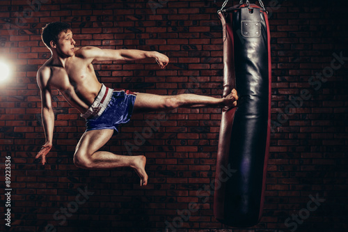 muscular handsome fighter giving a forceful forward kick during © satyrenko