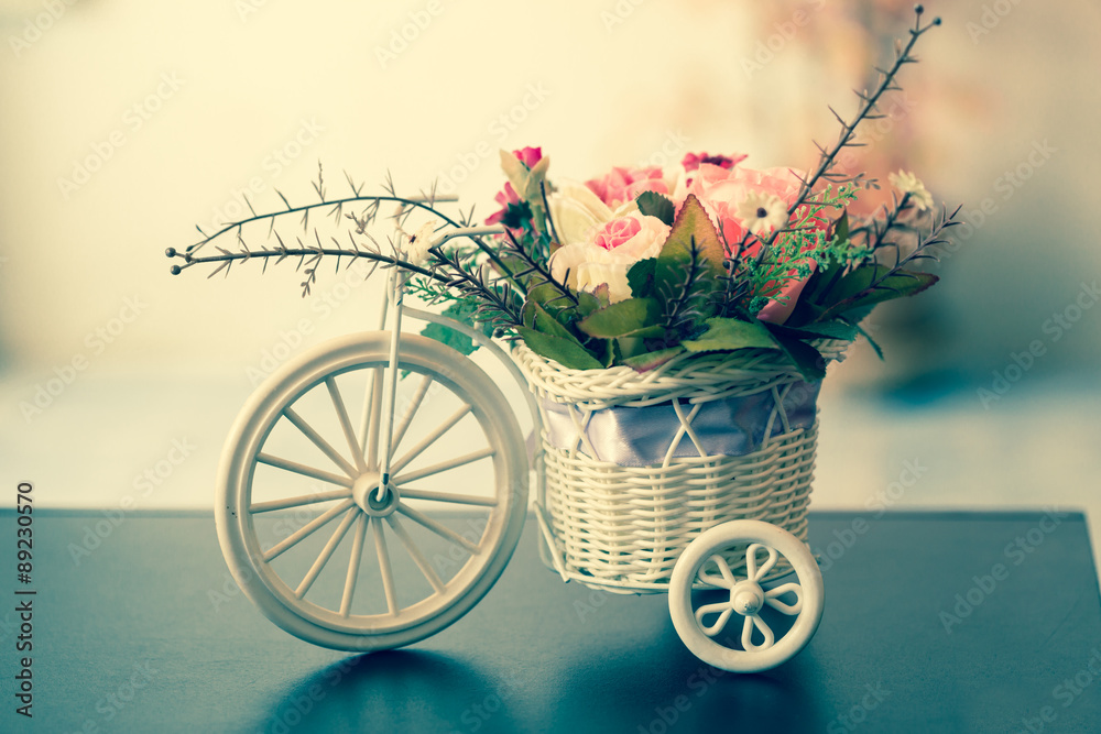Artificial flowers in a white Bicycle basket  on black table , v