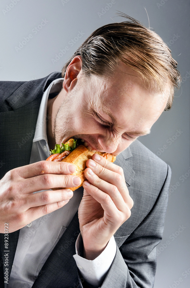 Man in suit eats BLT eagerly