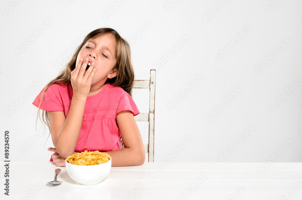 Tired young child with bowl of breakfast cereal