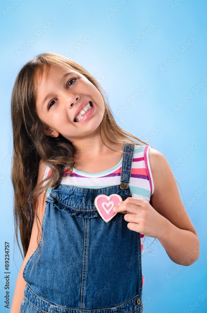 Smiling young girl puts cookies to heart Smiling young girl puts cookies to heart