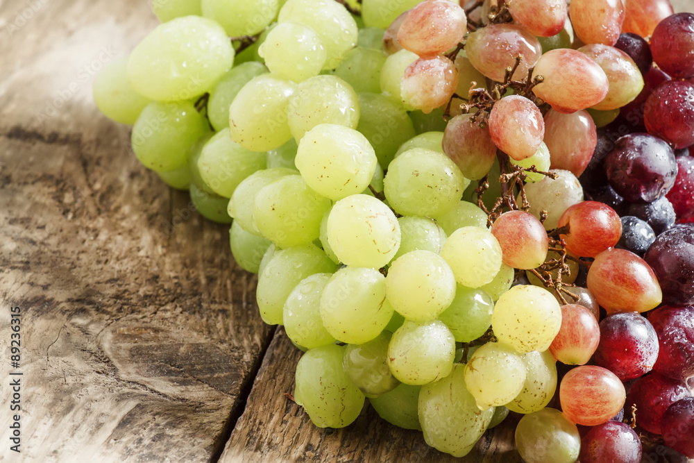 Green, pink and purple grapes on old wooden table, selective foc Green, pink and purple grapes on old wooden table, selective foc