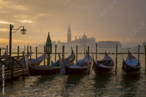Gondolas by Saint Mark square during sunrise with San Giorgio di Maggiore church in the background in Venice Italy © nexusseven