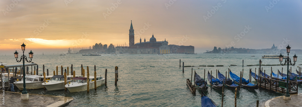 Naklejka premium Gondolas by Saint Mark square during sunrise with San Giorgio di Maggiore church in the background in Venice Italy