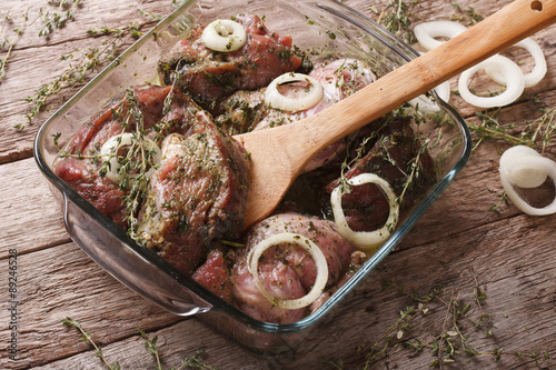 Billede på lærred Raw meat in a green marinade with onions in a bowl closeup