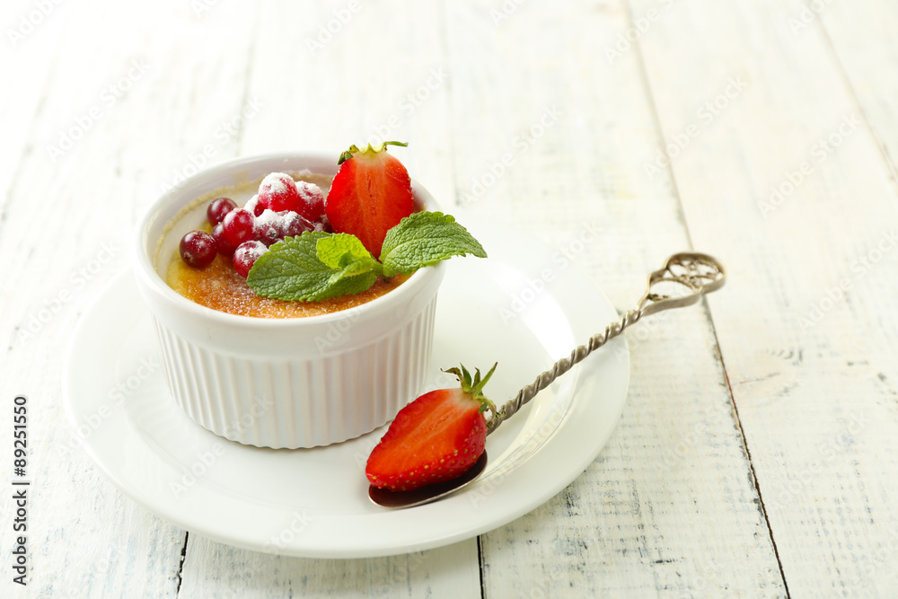 Creme brulee dessert with fresh strawberries and mint leaves, on color wooden background Creme brulee dessert with fresh strawberries and mint leaves, on color wooden background
