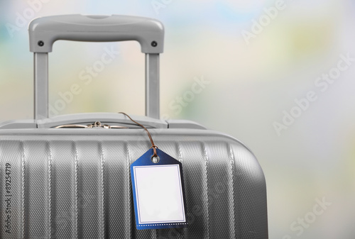 Foto Suitcase with TRAVEL INSURANCE label on light blurred background
