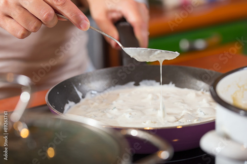 Woman cook sauce of gorgonzola in her kitchen