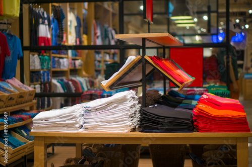 Variety of color t-shirts on table and stands in store